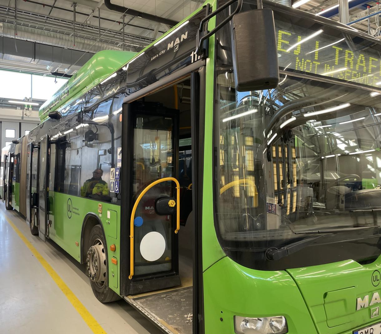 Modern turistbuss parkerad utanför en industribyggnad.